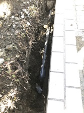 塀の下を潜って配管を再接続